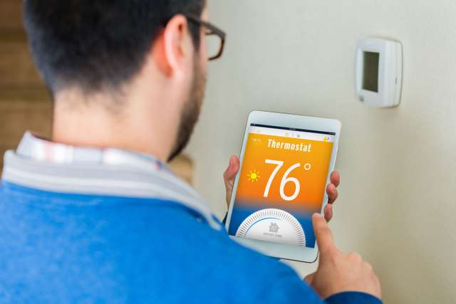 Homeowner adjusting a smart thermostat from a tablet